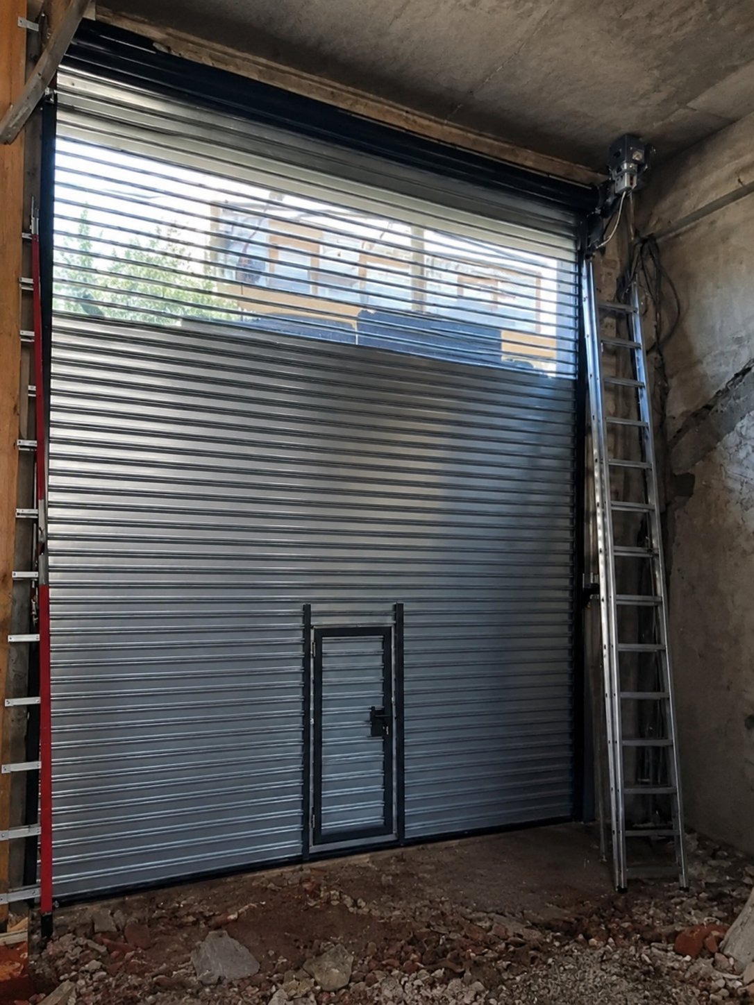 Cortina metálica de gran altura con puerta peatonal y motor, trabajo de Freedom Storm